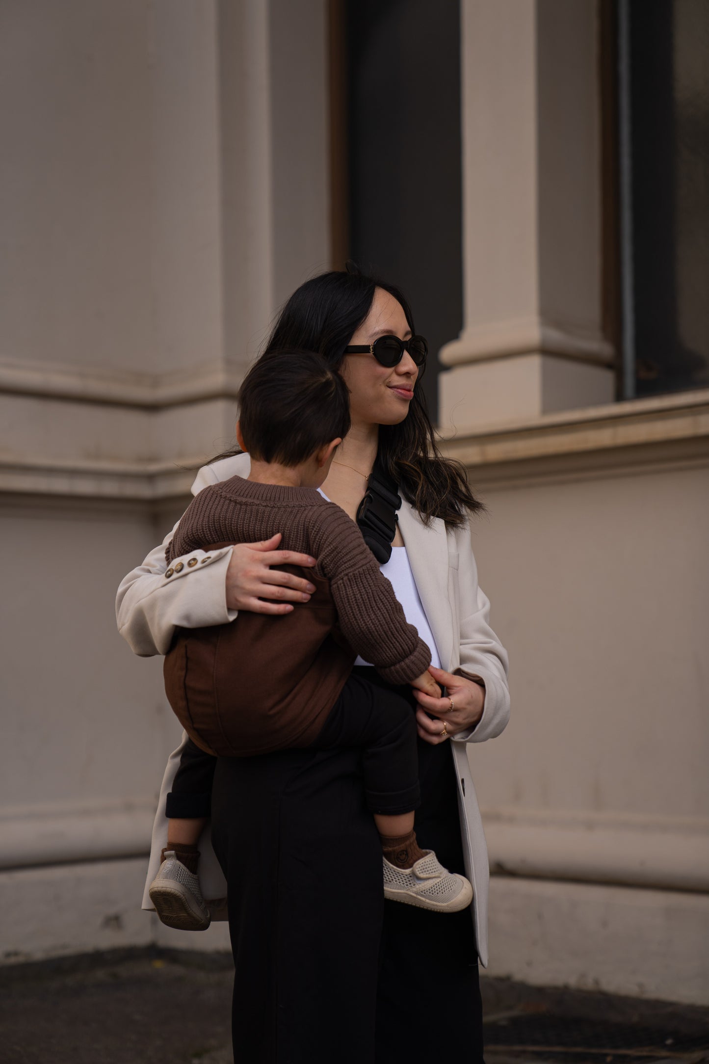 Parent carrying toddler in Brown Cuddl.bub Toddler Carrier/Toddler Sling