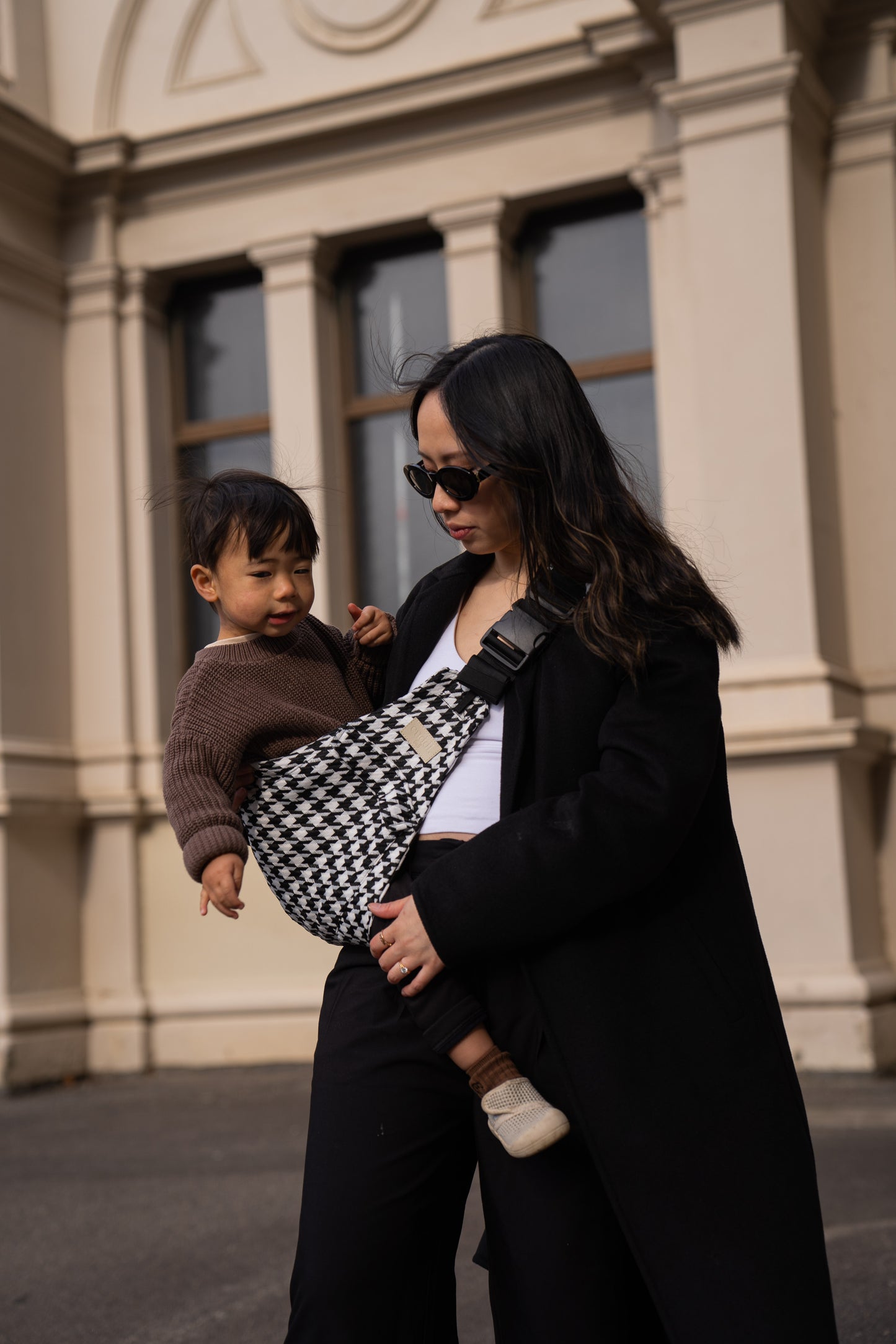Parent holding toddler in a Cuddl.bub Toddler Carrier/Toddler Sling black houndstooth