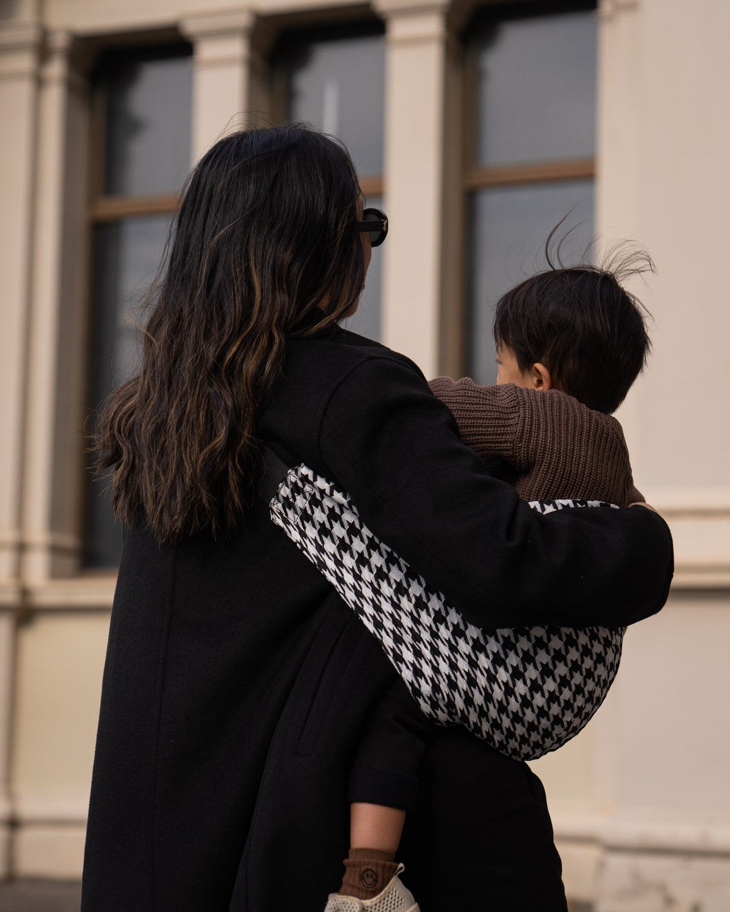 Back detail of Parent holding toddler in a Cuddl.bub Toddler Carrier/Toddler Sling black houndstooth