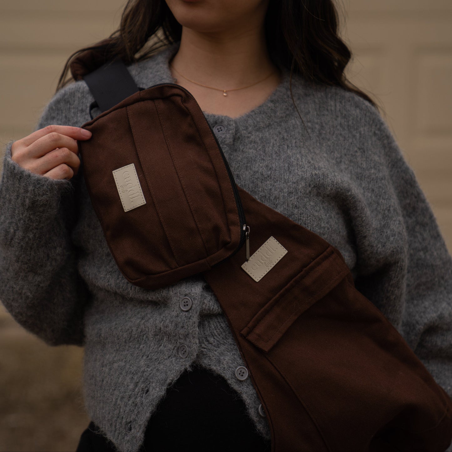 toddler parent wearing a chocolate brown/cocoa toddler carrier/toddler sling with a chocolate brown/cocoa slide on pouch