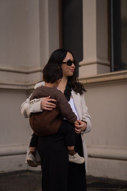 Parent carrying toddler in Brown Cuddl.bub Toddler Carrier/Toddler Sling