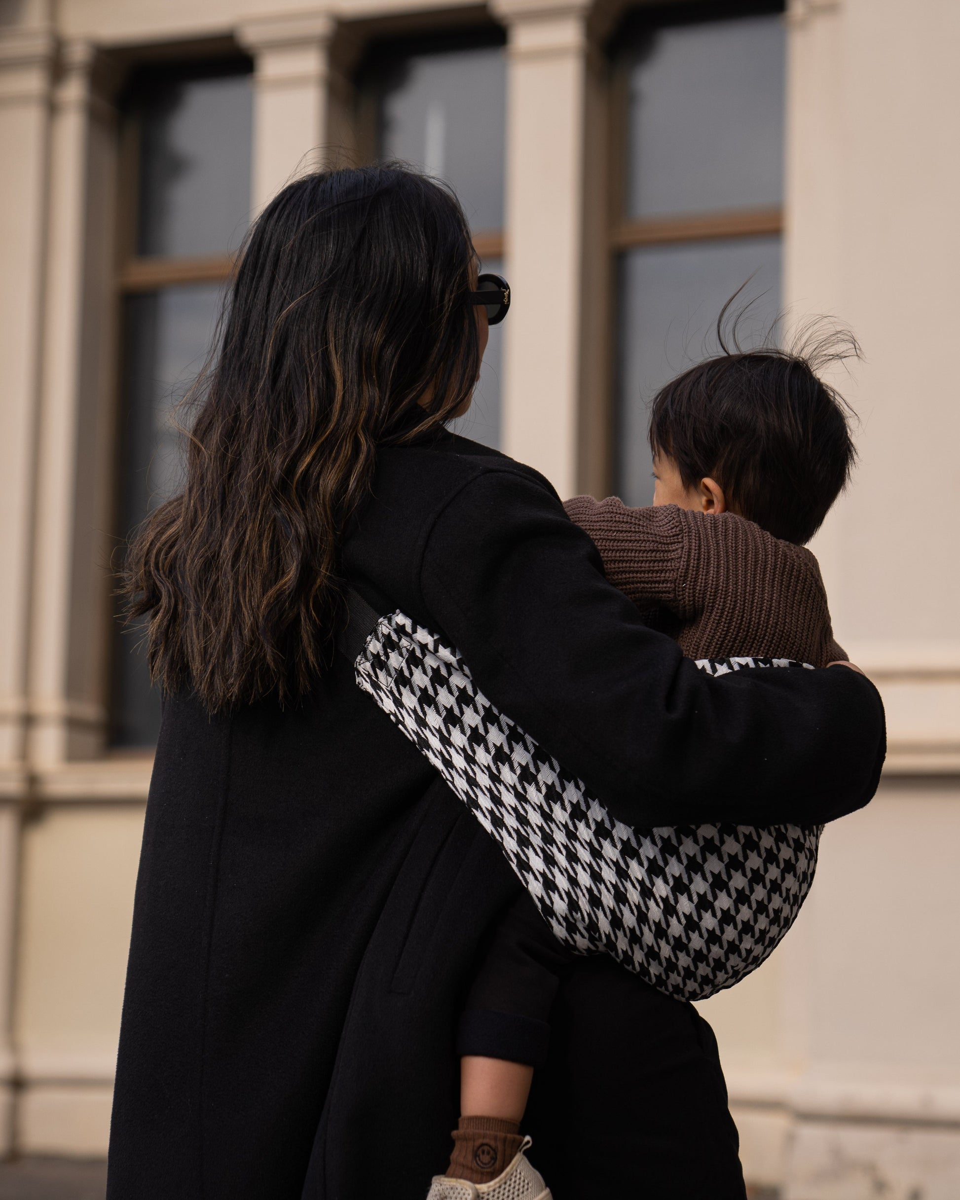 Back detail of Parent holding toddler in a Cuddl.bub Toddler Carrier/Toddler Sling black houndstooth