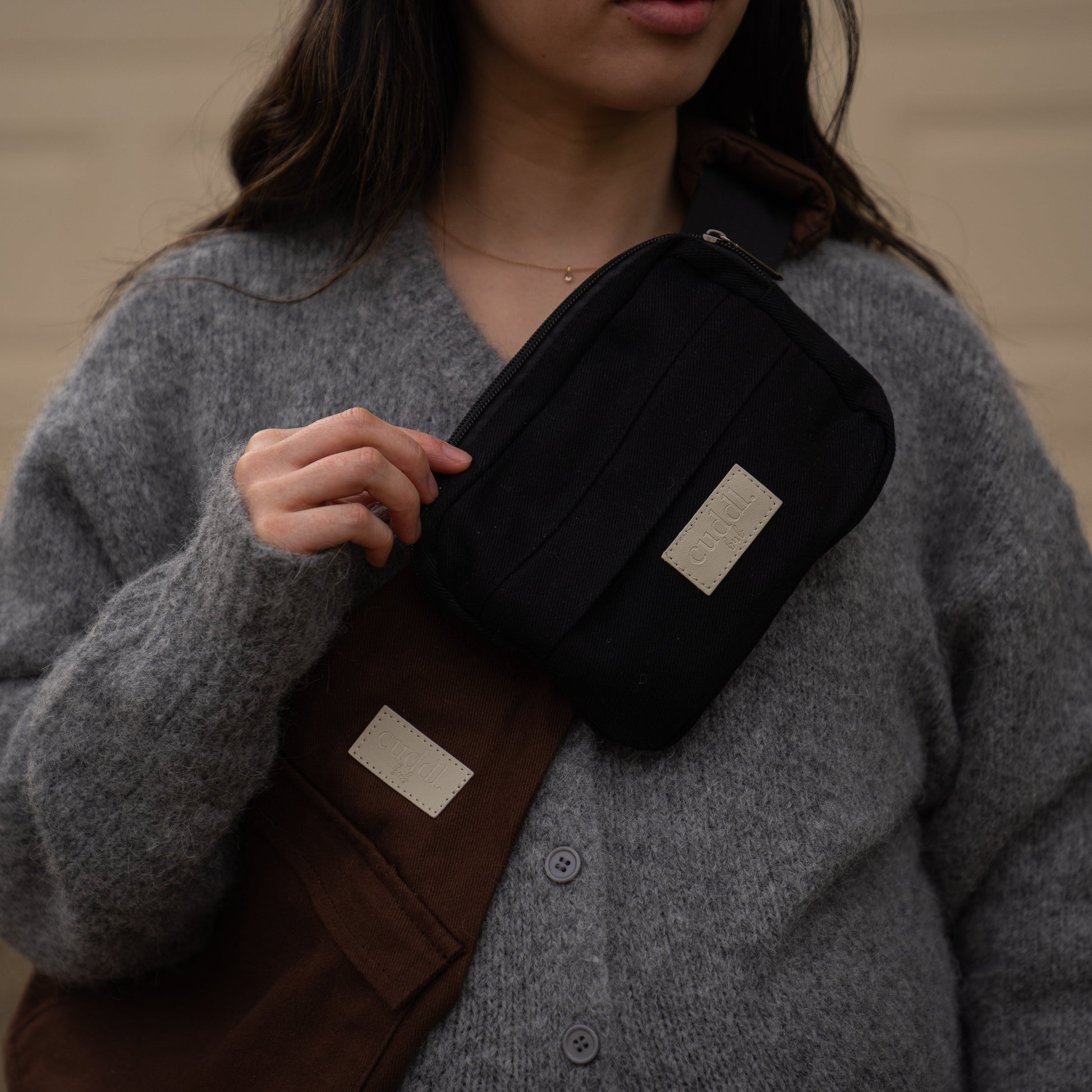 toddler parent wearing a chocolate brown/cocoa toddler carrier/toddler sling with a black slide on pouch