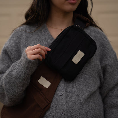 toddler parent wearing a chocolate brown/cocoa toddler carrier/toddler sling with a black slide on pouch