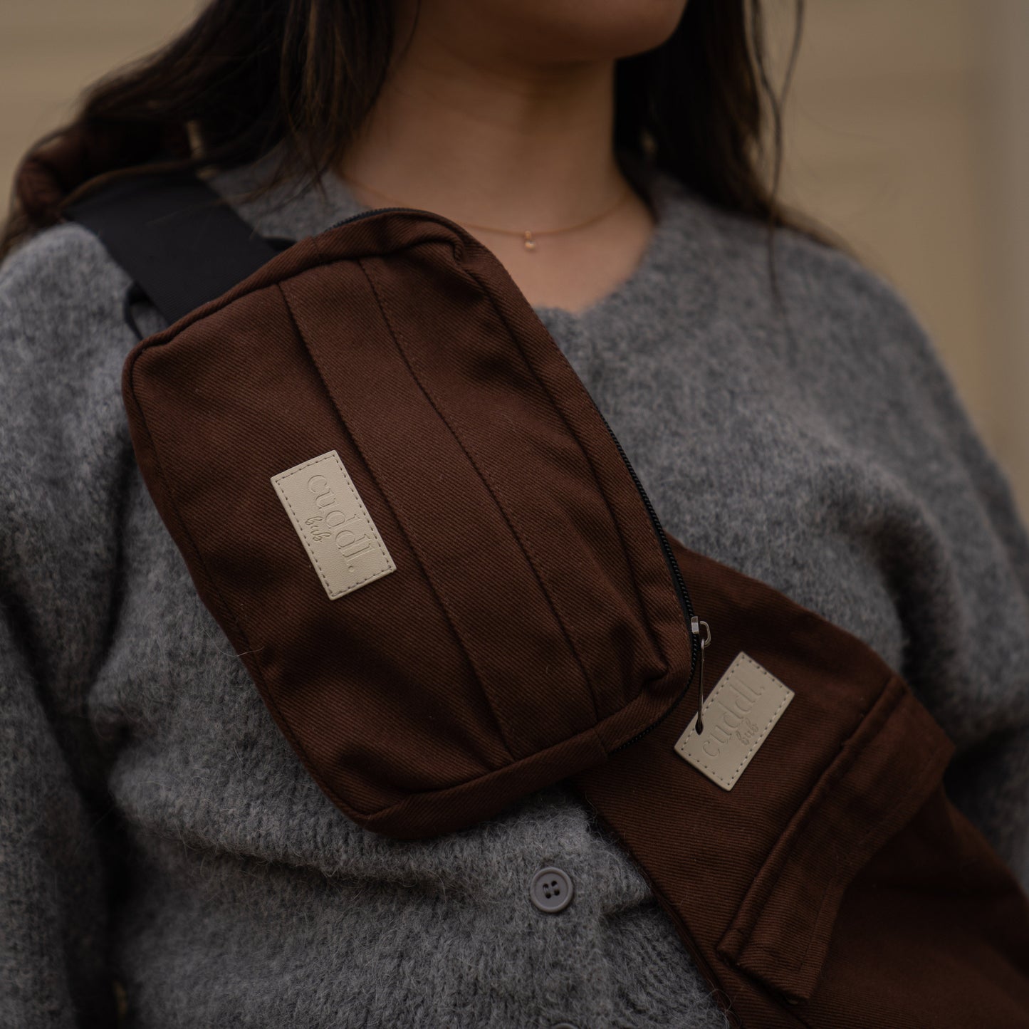 toddler parent wearing a chocolate brown/cocoa toddler carrier/toddler sling with a chocolate brown/cocoa slide on pouch