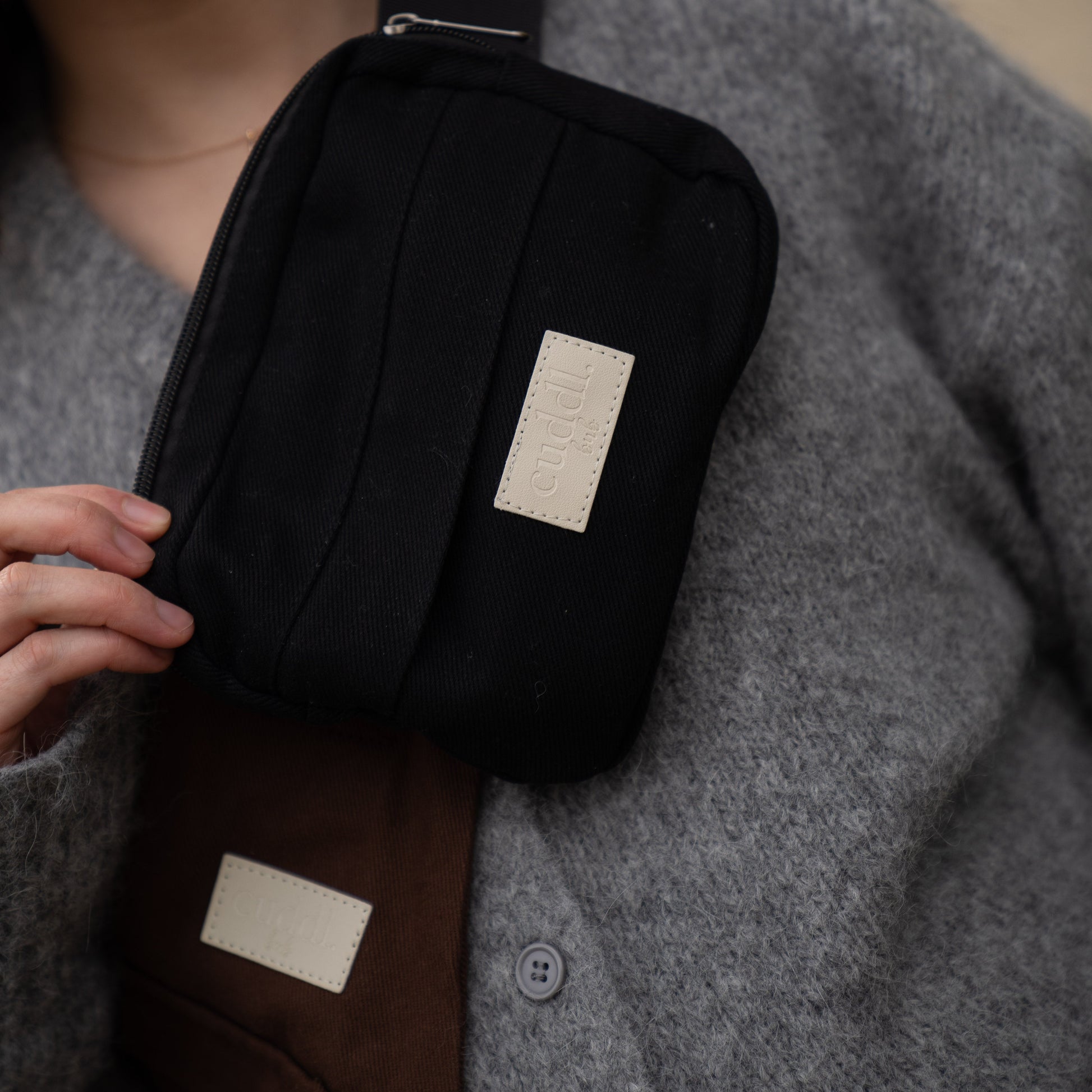 toddler parent wearing a chocolate brown/cocoa toddler carrier/toddler sling with a black slide on pouch