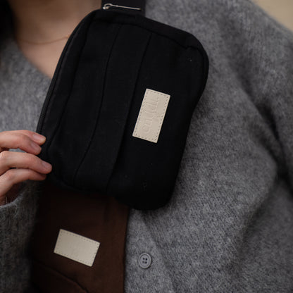 toddler parent wearing a chocolate brown/cocoa toddler carrier/toddler sling with a black slide on pouch